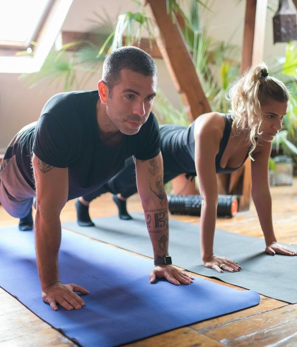 Man in a seated meditation pose on a yoga mat with serene cyan lighting.